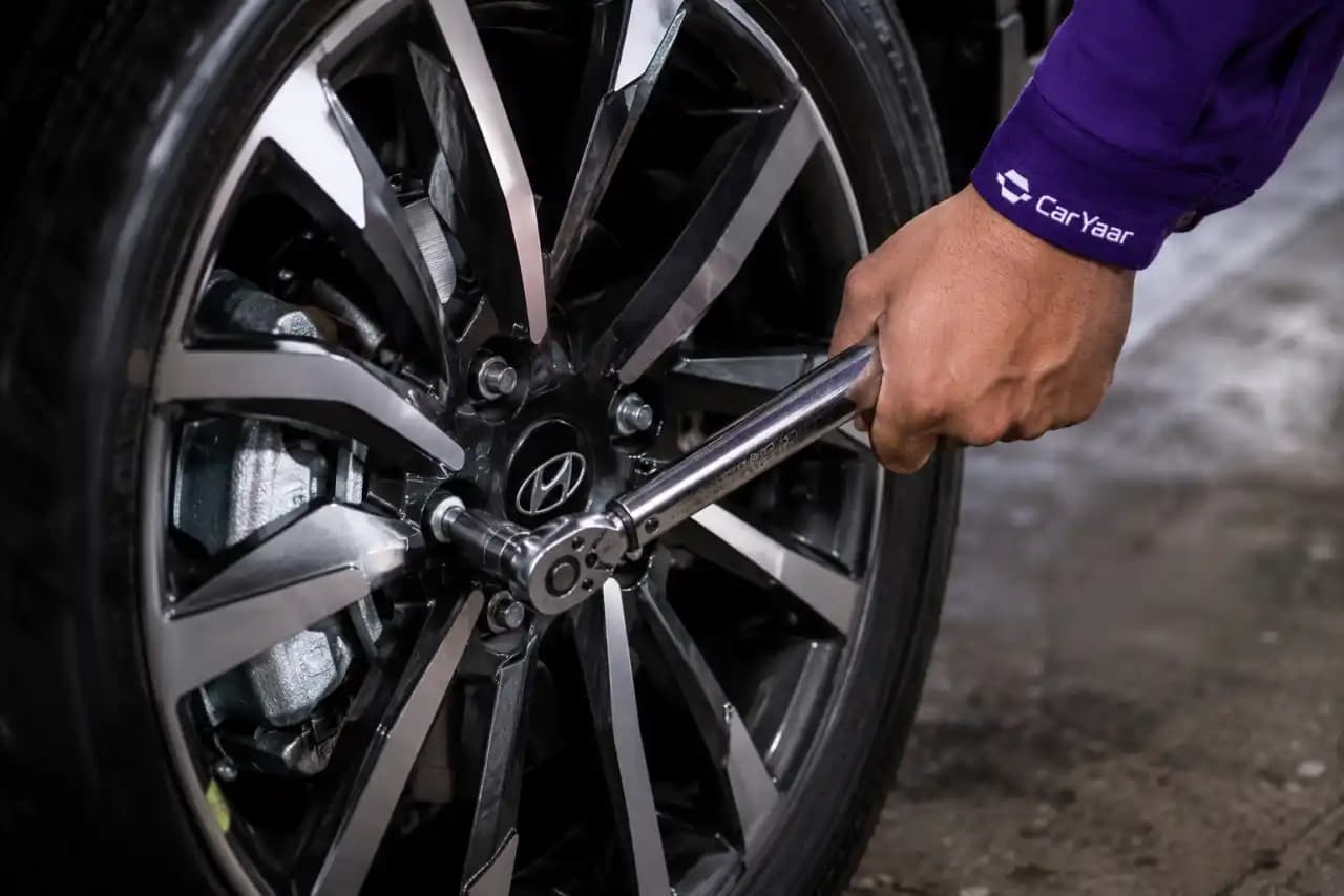 Closeup of a CarYaar technician using a torque wrench on an alloy wheel.