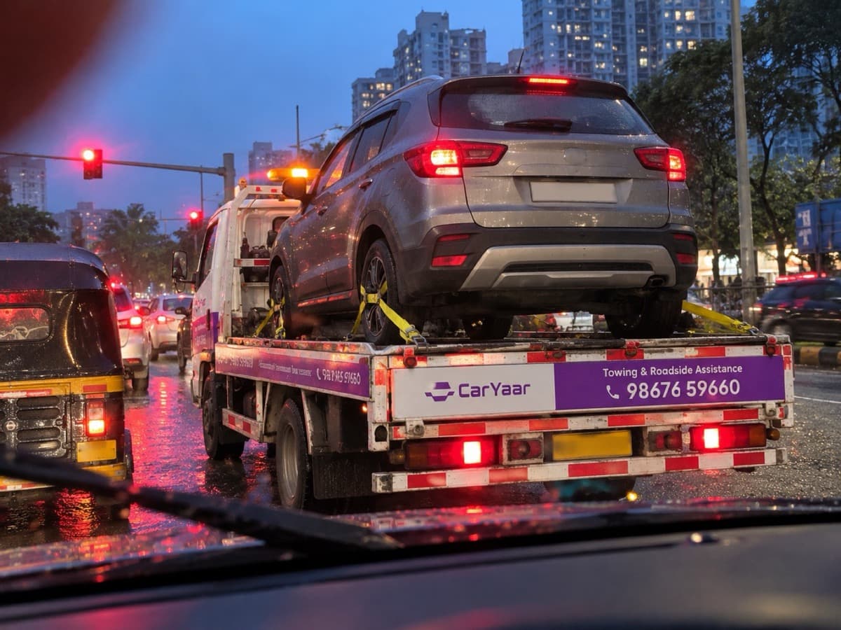 A CarYaar flatbed carrying a Creta through evening rain traffic in Mumbai