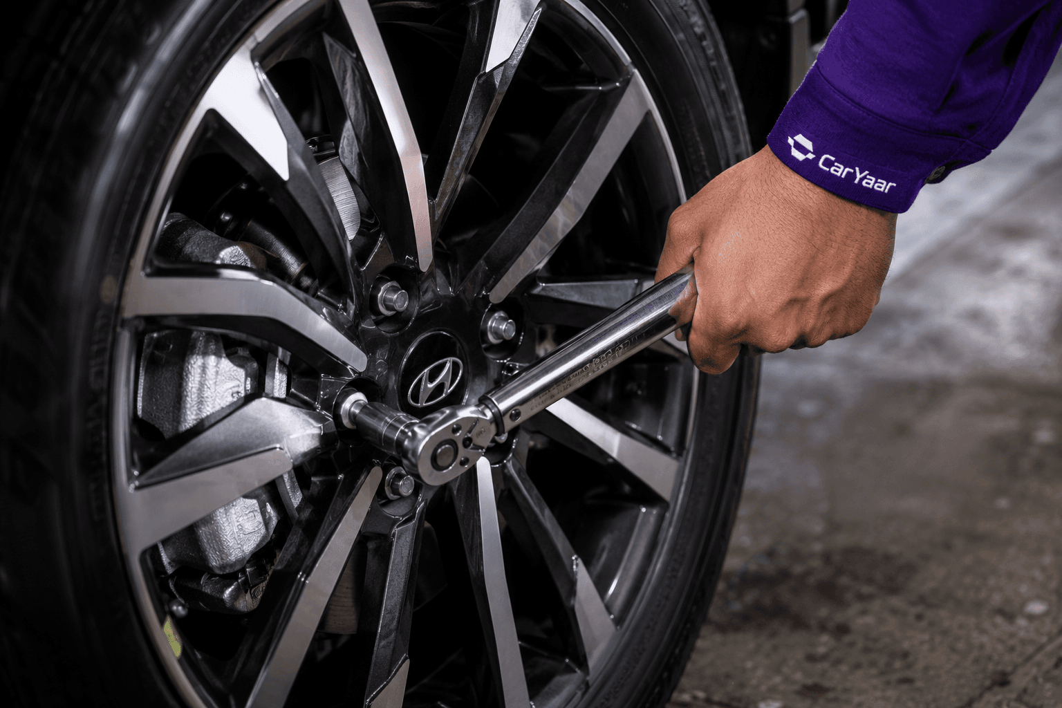 Closeup of a CarYaar technician using a torque wrench on an alloy wheel.